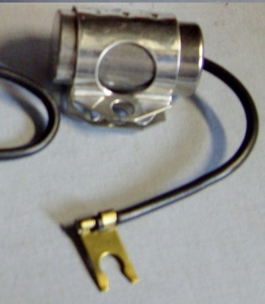 A silver 1930s-60s Delco Remy style 6 & 8 cyl. distributor condenser with a wire attached to it.